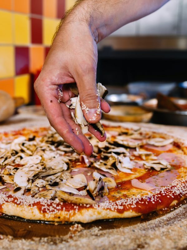 Putting Mushrooms On Pizza In Pizza Restaurant